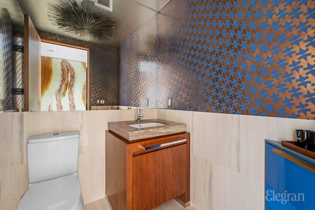 bathroom featuring tile walls, toilet, and vanity