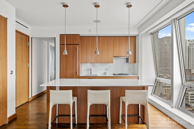 kitchen with dark hardwood / wood-style floors, a center island, hanging light fixtures, and tasteful backsplash