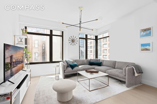 living room featuring a wealth of natural light, light hardwood / wood-style floors, and a notable chandelier