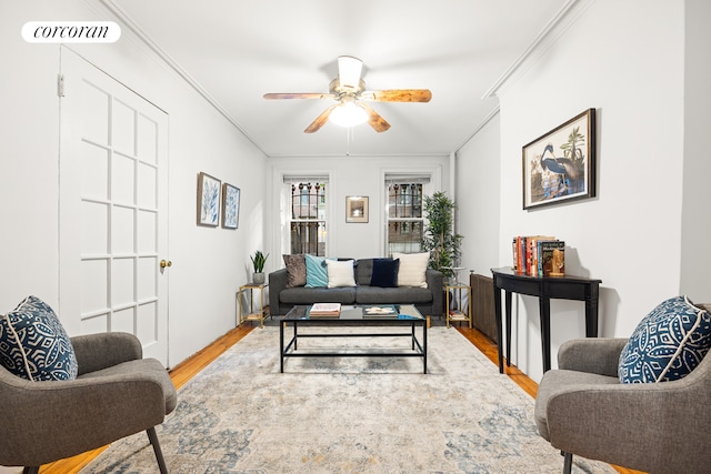 living room with wood-type flooring, ceiling fan, and ornamental molding