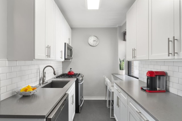 kitchen with backsplash, appliances with stainless steel finishes, dark tile floors, and white cabinets