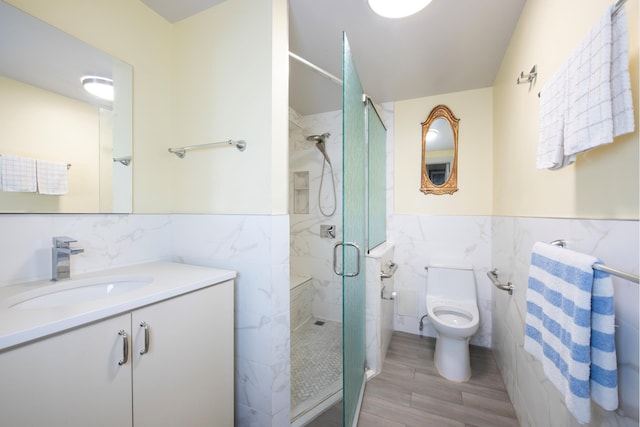 bathroom featuring wood-type flooring, vanity, toilet, and tile walls