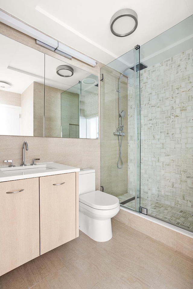 bathroom featuring vanity, a shower with shower door, tile walls, and toilet