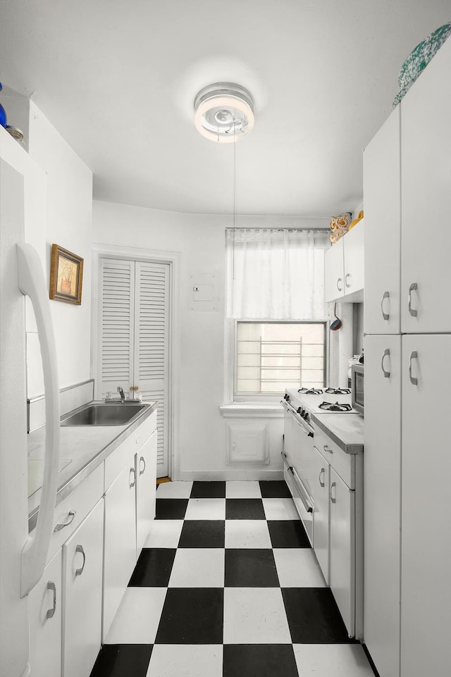 kitchen featuring white cabinetry, white fridge, sink, and dark tile patterned flooring