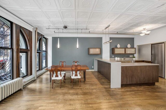 dining space with light hardwood / wood-style floors, track lighting, radiator, and ceiling fan