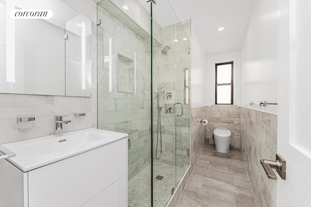 bathroom featuring tile floors, tile walls, vanity, and a shower with door