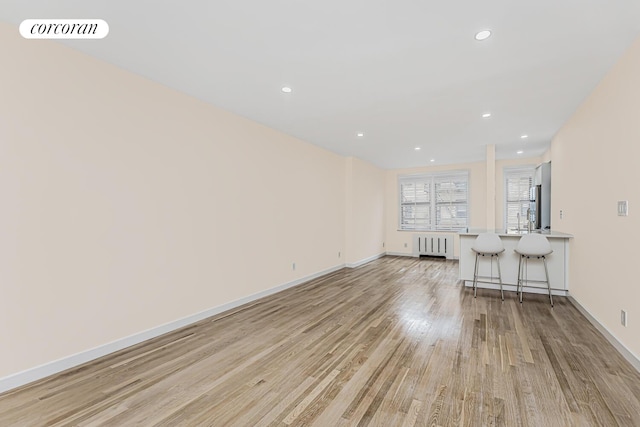 unfurnished living room featuring radiator and light hardwood / wood-style flooring