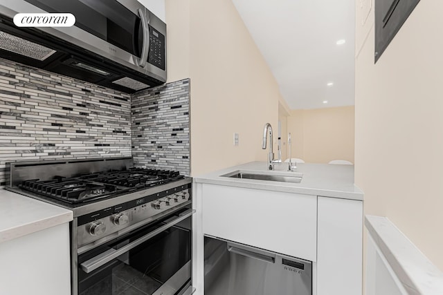 kitchen featuring appliances with stainless steel finishes, white cabinetry, sink, and backsplash