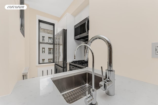 interior details featuring light stone counters, appliances with stainless steel finishes, and sink