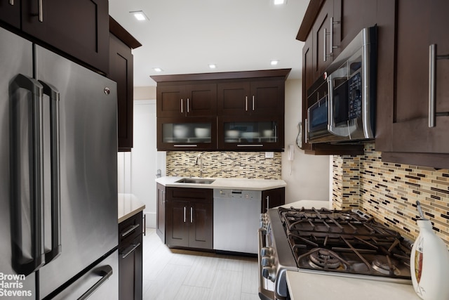 kitchen with dark brown cabinets, tasteful backsplash, light tile floors, sink, and appliances with stainless steel finishes