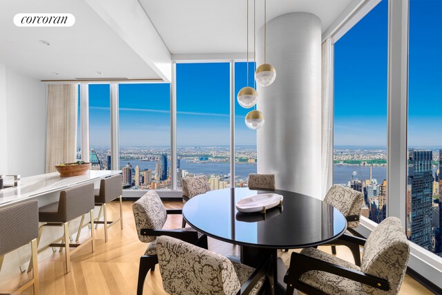 dining room with floor to ceiling windows, a water view, and light hardwood / wood-style flooring