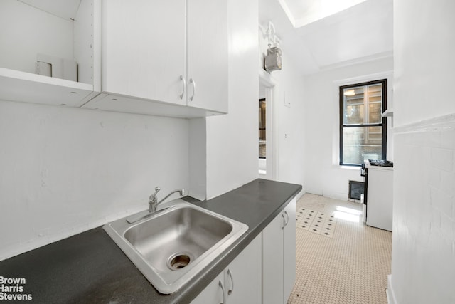 kitchen featuring light tile patterned flooring, white gas stove, sink, and white cabinets