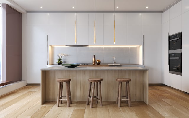 kitchen with light hardwood / wood-style flooring, a center island with sink, white cabinets, and tasteful backsplash