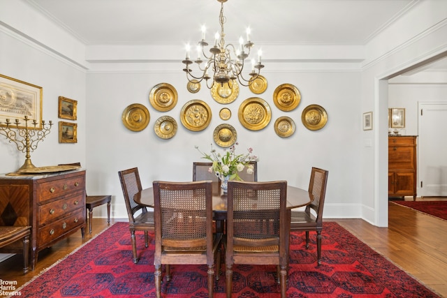 dining area with a notable chandelier, ornamental molding, and wood-type flooring