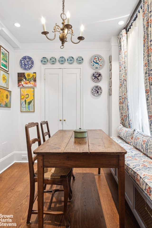 dining area with ornamental molding, an inviting chandelier, and wood-type flooring