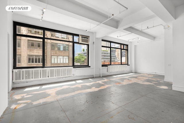 empty room featuring beam ceiling and concrete floors