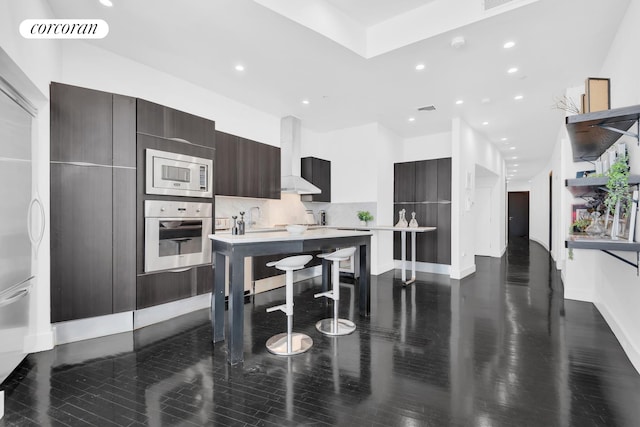 kitchen with appliances with stainless steel finishes, backsplash, dark brown cabinetry, dark wood-type flooring, and custom exhaust hood