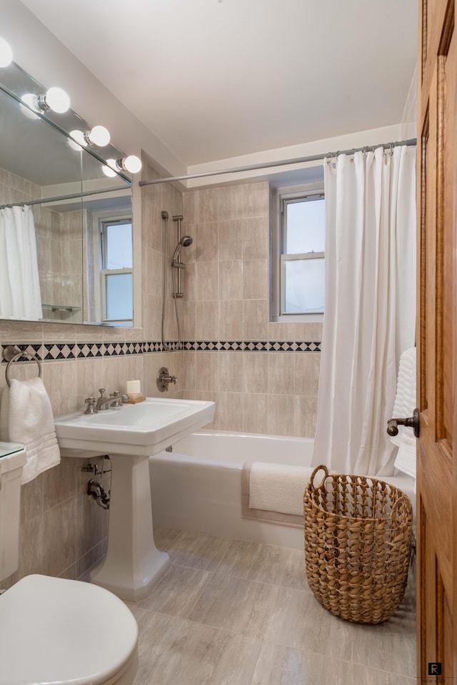 bathroom featuring toilet, shower / bathtub combination with curtain, tile patterned flooring, and tile walls