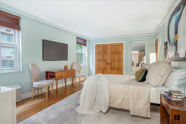 bedroom with a closet, hardwood / wood-style floors, and ornamental molding