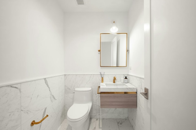 bathroom featuring vanity, toilet, tile patterned floors, and tile walls