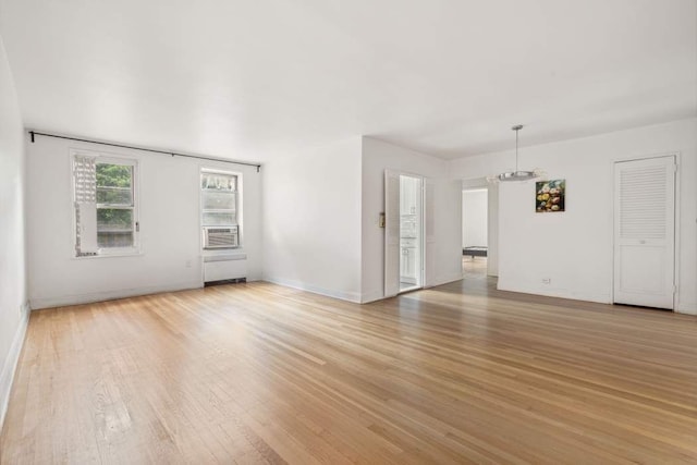 unfurnished living room with light hardwood / wood-style flooring and a chandelier