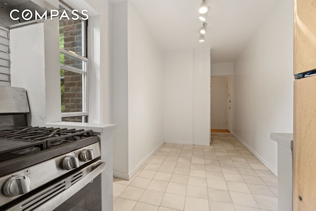 kitchen featuring a healthy amount of sunlight, light tile patterned floors, rail lighting, and stainless steel range with gas stovetop