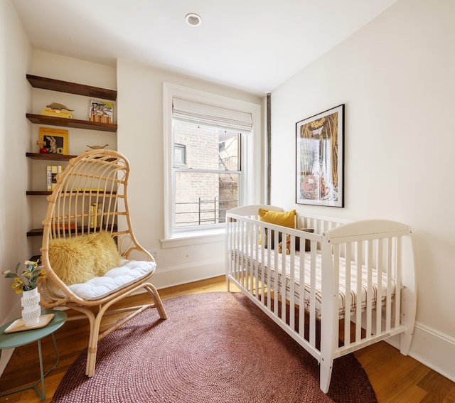 bedroom featuring a nursery area and wood-type flooring