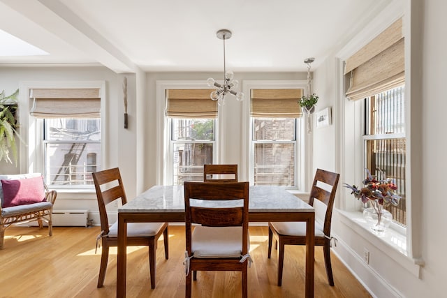 dining room featuring plenty of natural light, wood-type flooring, and an inviting chandelier