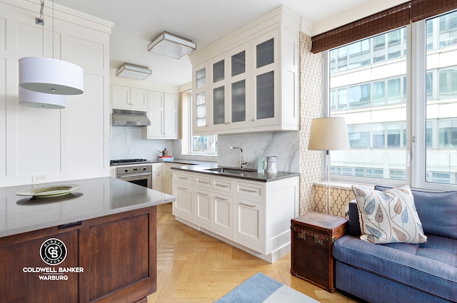 kitchen featuring stainless steel oven, light parquet flooring, white cabinets, and wall chimney exhaust hood