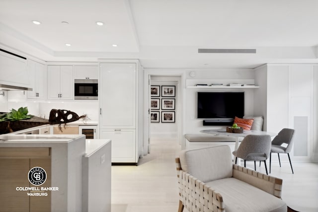 kitchen featuring white cabinets, light hardwood / wood-style floors, a kitchen breakfast bar, wine cooler, and built in microwave