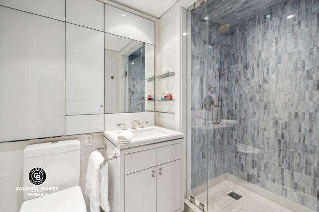 bathroom with vanity, toilet, walk in shower, and tile walls