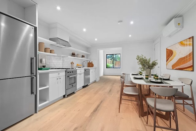 kitchen featuring appliances with stainless steel finishes, decorative backsplash, white cabinets, and light wood-type flooring