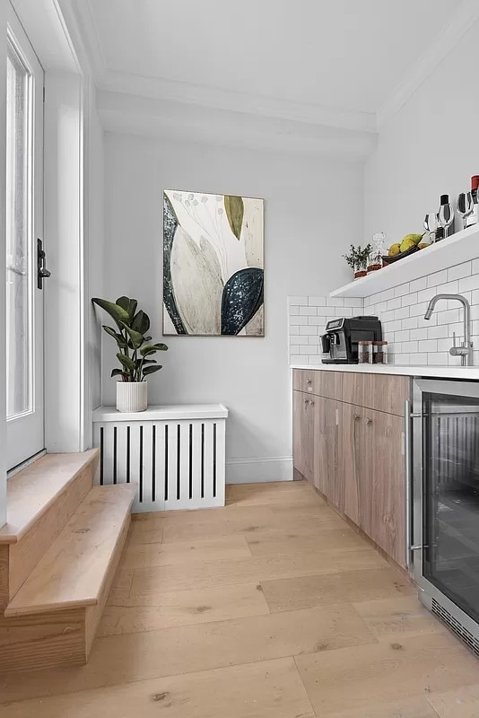 bar with sink, backsplash, light wood-type flooring, beverage cooler, and ornamental molding