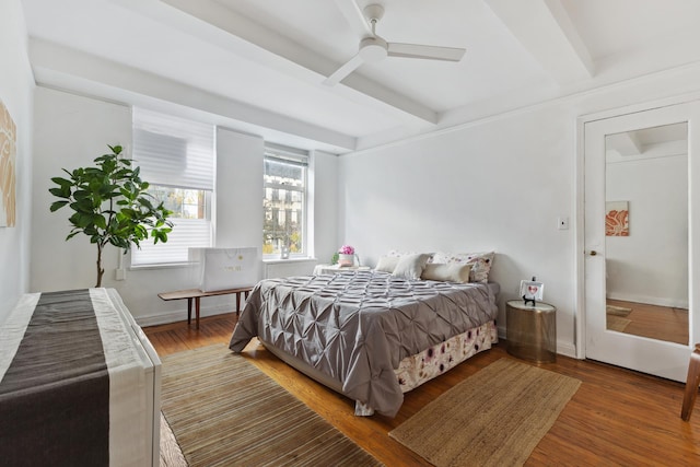 bedroom with beamed ceiling, wood-type flooring, and ceiling fan