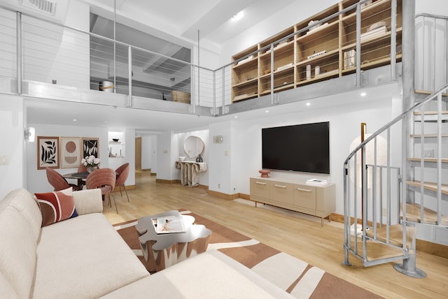 living room with light hardwood / wood-style flooring and a towering ceiling