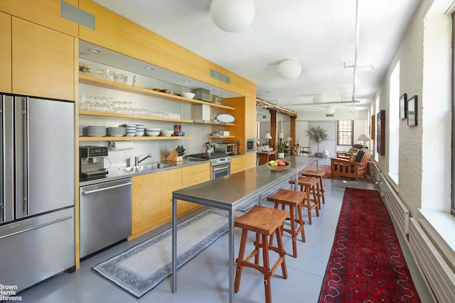 kitchen featuring stainless steel counters, sink, stainless steel appliances, and brick wall