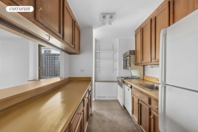 kitchen featuring a textured ceiling, sink, and white appliances