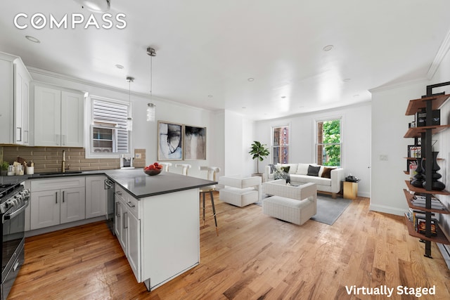 kitchen with light hardwood / wood-style flooring, a kitchen bar, stainless steel appliances, decorative backsplash, and sink