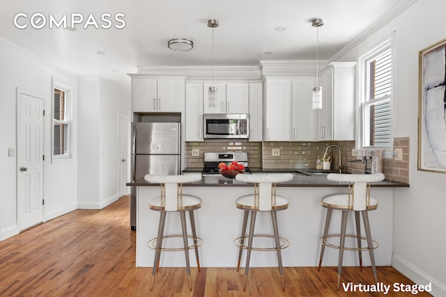 kitchen with a breakfast bar area, white cabinets, kitchen peninsula, and stainless steel appliances