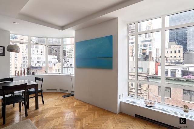 interior space with light parquet flooring, a tray ceiling, and radiator