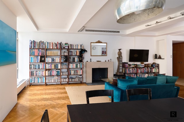 living room with light parquet flooring, a high end fireplace, radiator, and a tray ceiling