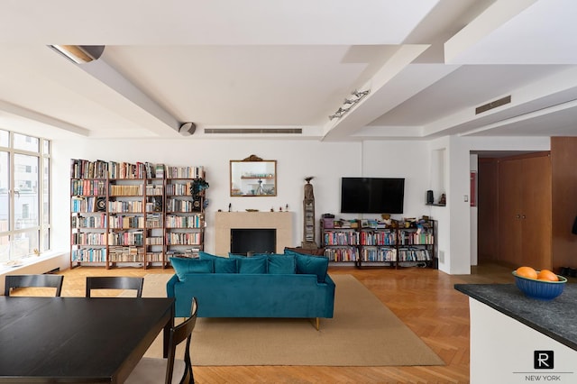 living room with a raised ceiling, light parquet flooring, and rail lighting