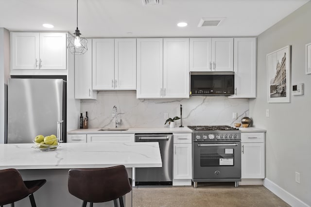 kitchen featuring tasteful backsplash, white cabinets, hanging light fixtures, and appliances with stainless steel finishes