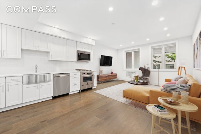 kitchen with white cabinets, hardwood / wood-style flooring, appliances with stainless steel finishes, and sink