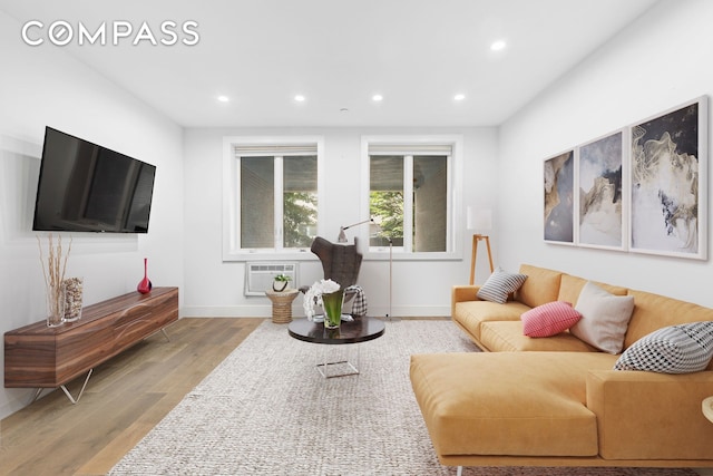 living room featuring a wall mounted AC and light hardwood / wood-style floors