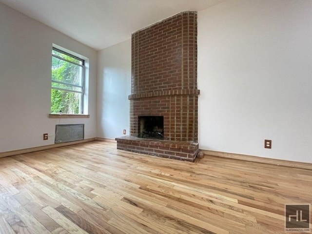 unfurnished living room featuring a fireplace, hardwood / wood-style floors, and lofted ceiling