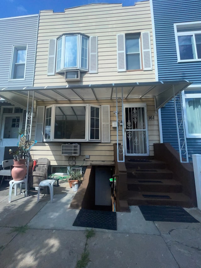 view of front of house featuring a patio area and a wall mounted air conditioner