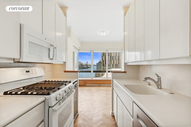 kitchen featuring white cabinetry, light parquet floors, white appliances, and sink