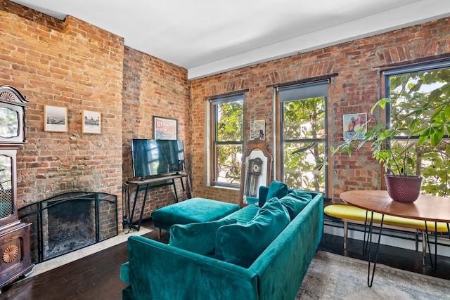 living room with dark hardwood / wood-style flooring, a healthy amount of sunlight, and brick wall