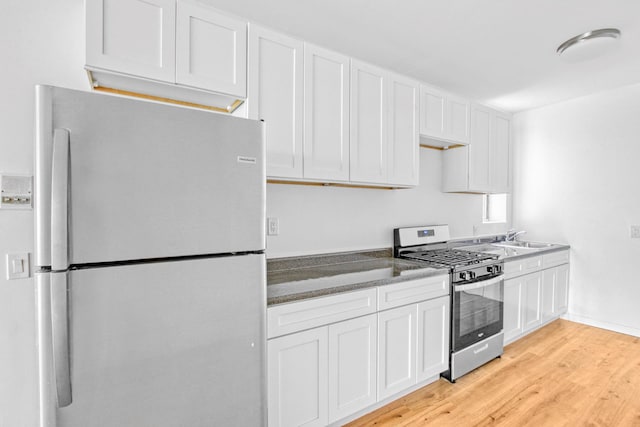 kitchen featuring white fridge, white cabinets, light hardwood / wood-style flooring, and stainless steel range with gas stovetop